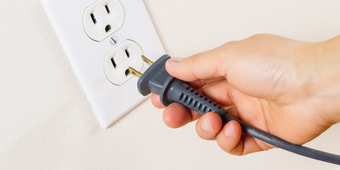 person putting plug into outlet