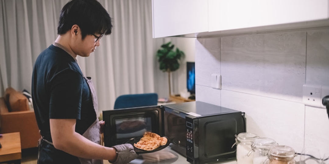 man pulling food out of microwave