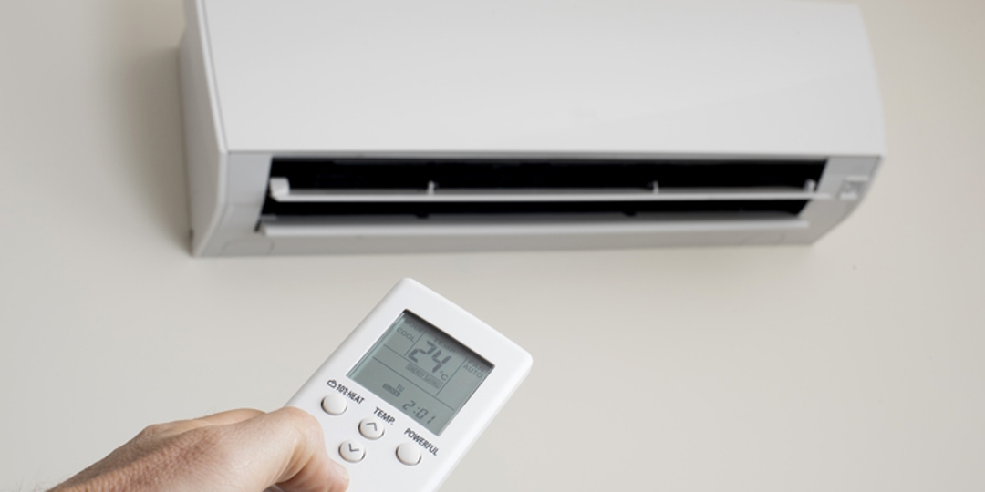 Person aiming a remote at their AC unit