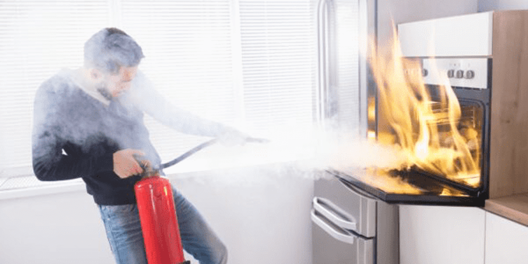 A man putting out a fire started in the oven