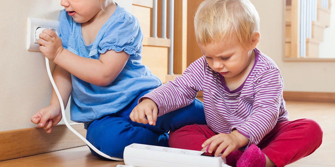 Two children playing near an outlet