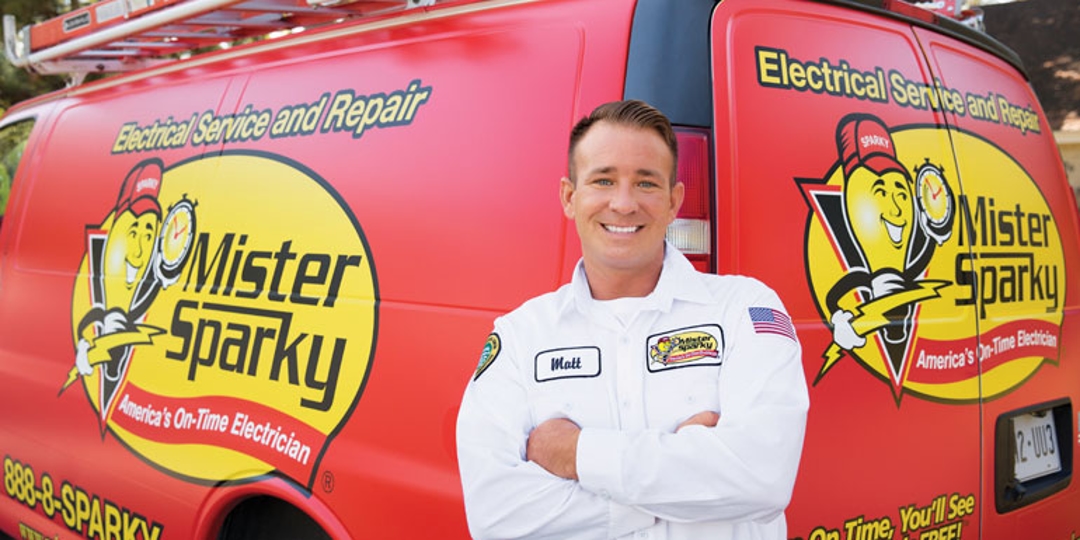 Mister Sparky electrician standing outside the corner of the company vehicle