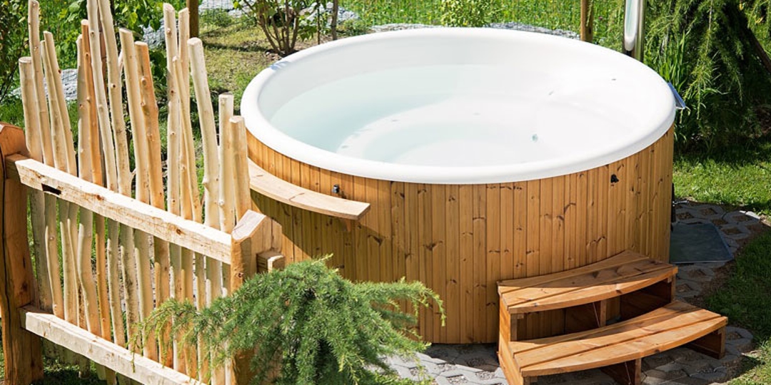 Outdoor hot tub made of wood with steps leading into it