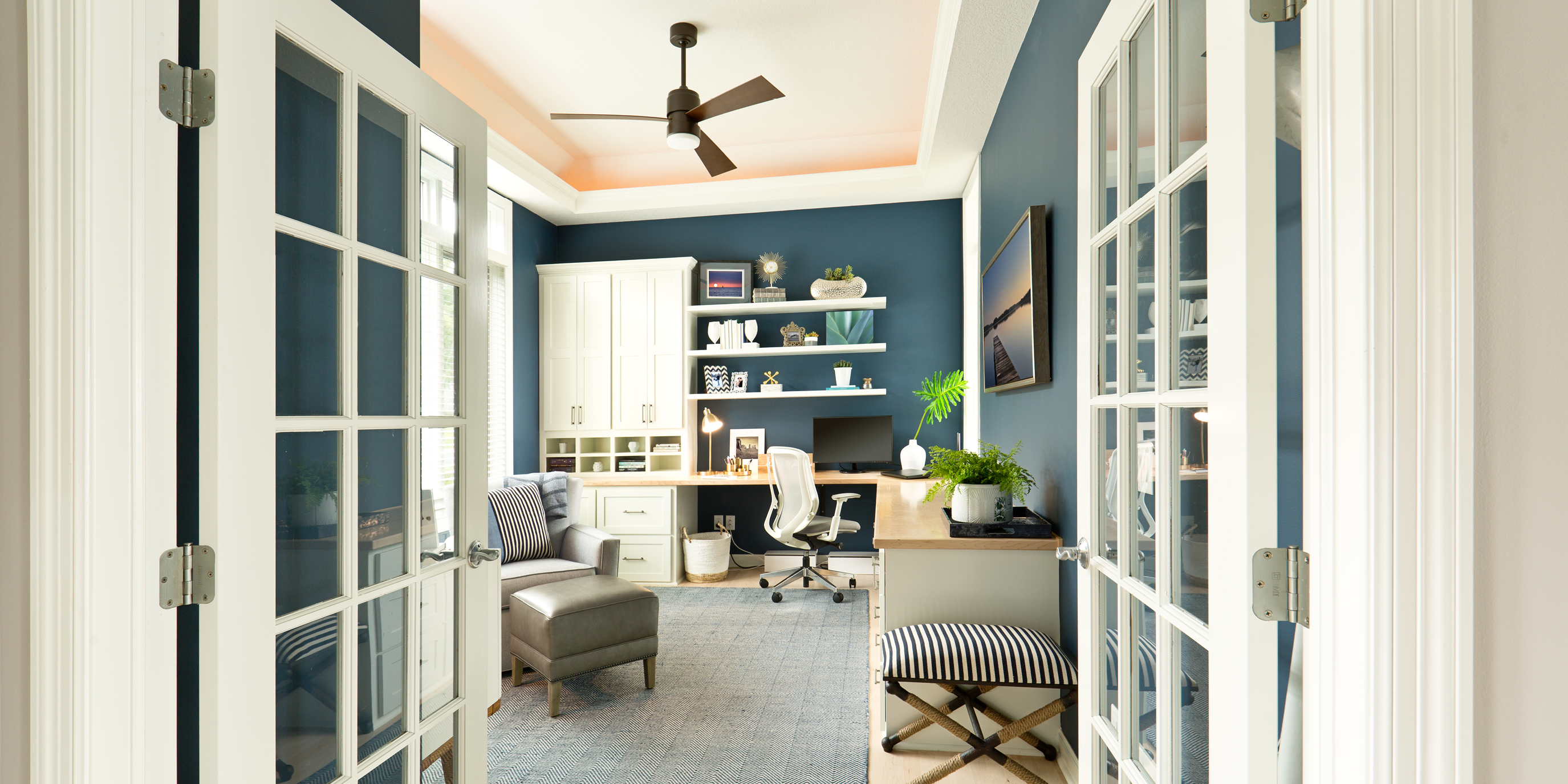 A sunny room has a three-blade ceiling fan.